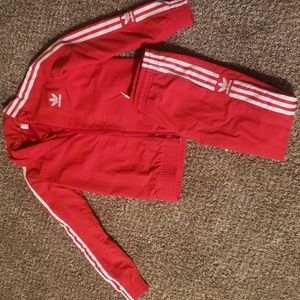 Red and white Adidas sweatsuit and white adidas shoes.